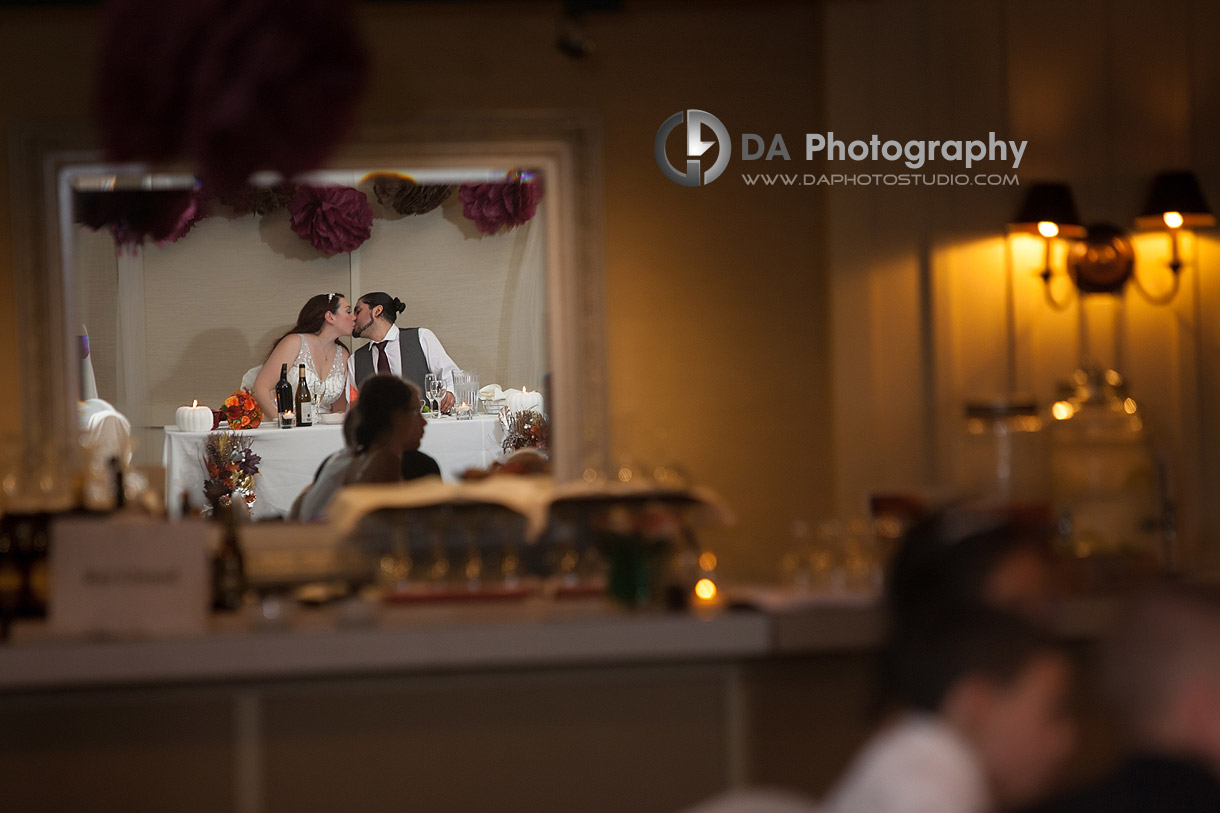 Reception kiss captured though the reflection on the next wall mirrors - by DA Photography at Black Creek Pioneer Village, www.daphotostudio.com