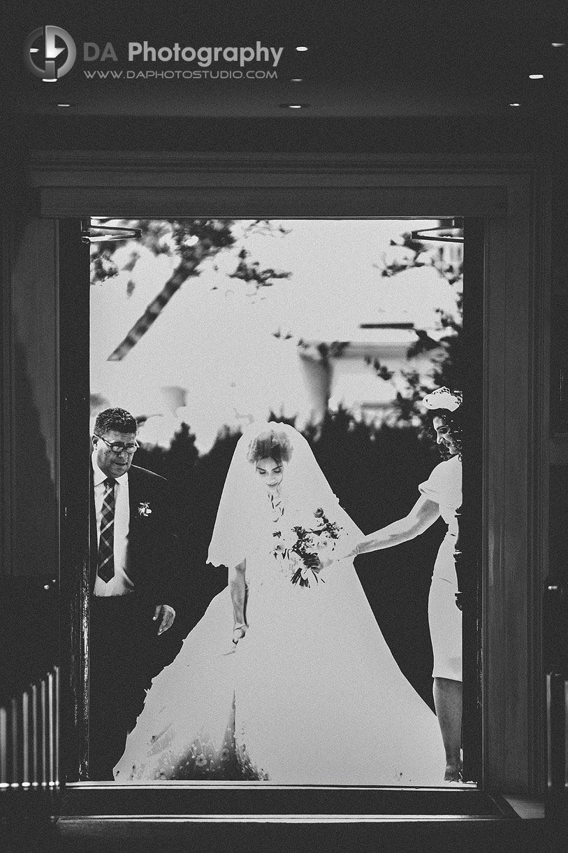 Bride with her parents entering a church for a wedding ceremony