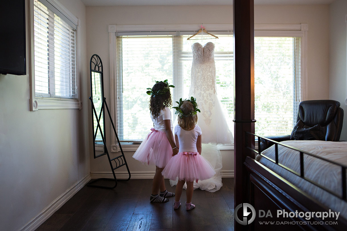 Flower girls looking at a wedding dress hanged up