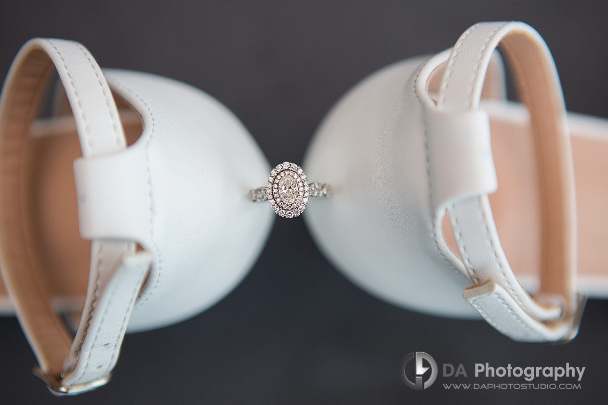 Close up photo of an engagement ring in between wedding shoes