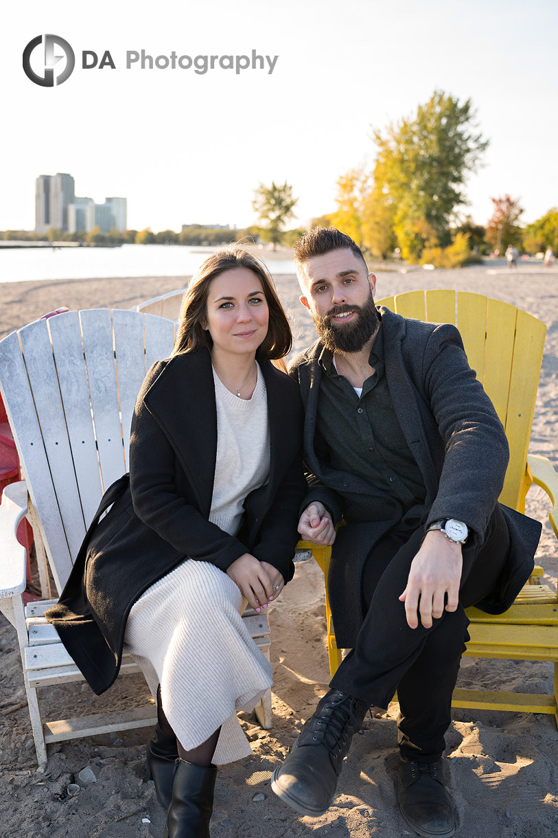 Engaged couple sitting on Muskoka chairs on the beach