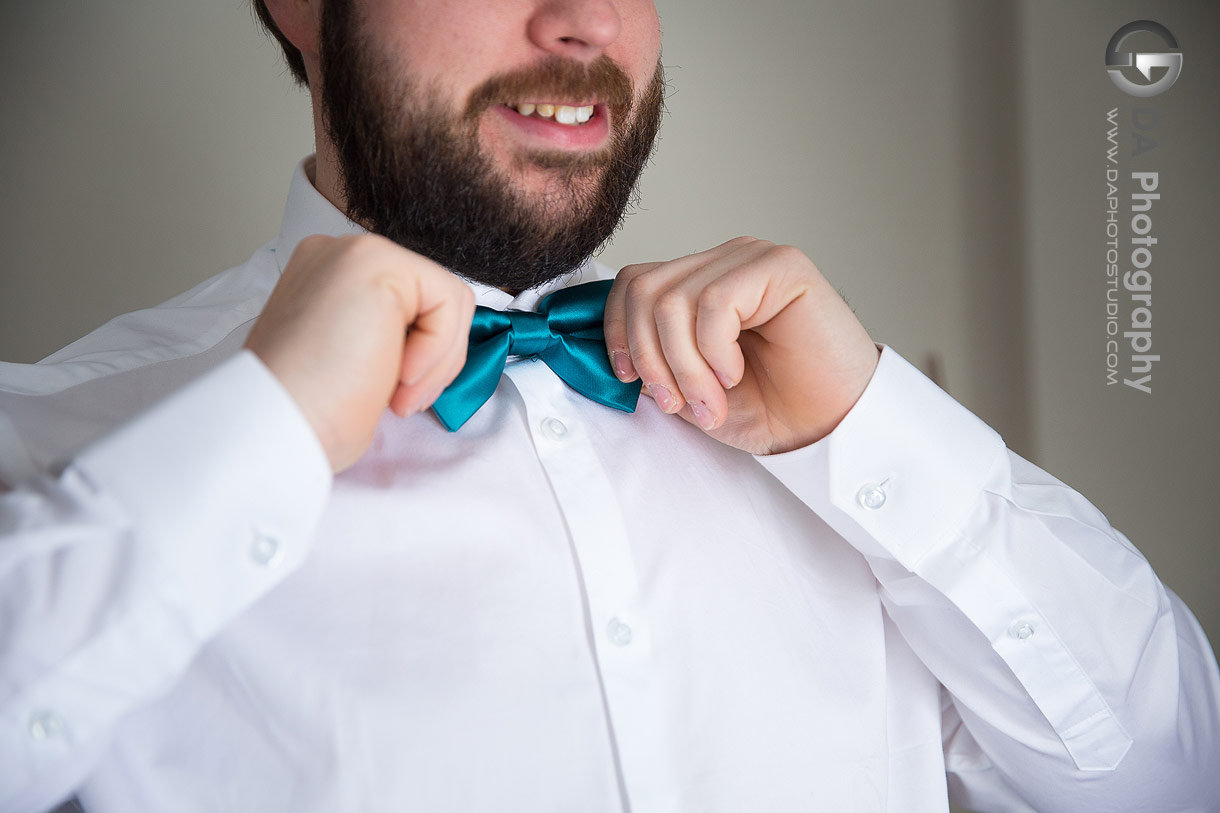 Groom adjusting his bowtie at Hilton Garden Inn in Cambridge