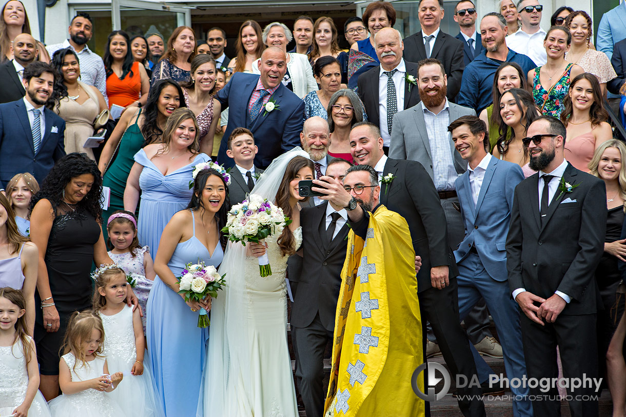 Selfie of a priest with the bride and groom in front of a church